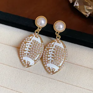Close-up of elegant rugby-shaped pearl earrings with gold-tone and white enamel