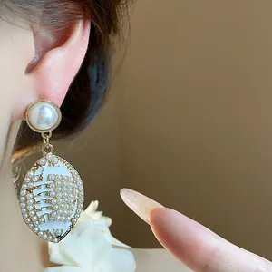 Detailed view of elegant football-shaped pearl drop earrings with premium golden finish.