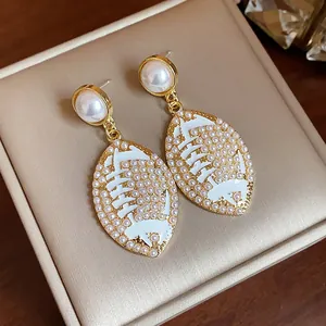 Close-up of elegant oval earrings featuring white enamel and tiny pearl accents.
