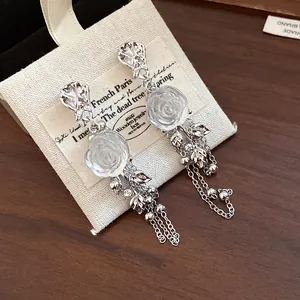 Detailed macro shot of French style resin flower earrings with silver tassel chains