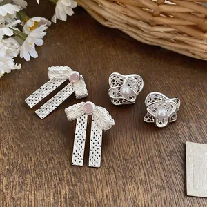 Primo piano di eleganti orecchini a fiocco d'argento e fiori di perla su tavolo legno