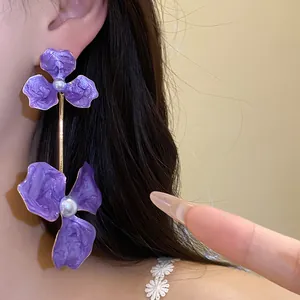 Detail von übergroßen lila Blumenohrringen mit Perlen und goldener Hängeleiste