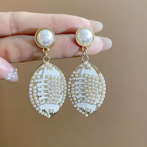 Detailed macro view of elegant gold pearl drop earrings with football-shaped enamel