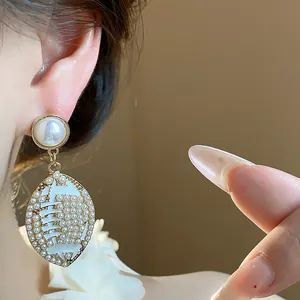 Close-up view of elegant rugby shaped pearl earrings with white enamel dripping oil