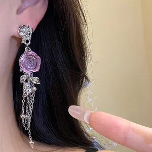 Close-up of elegant pink resin rose earrings with long hanging silver tassel chains