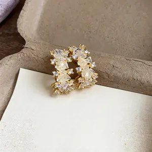 Detail view of 14k gold plated earrings with sparkling zircon stones on a cream card