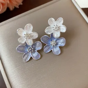 Nahaufnahme von eleganten blau-weißen Blumenohrsteckern mit strukturierten Blütenblättern