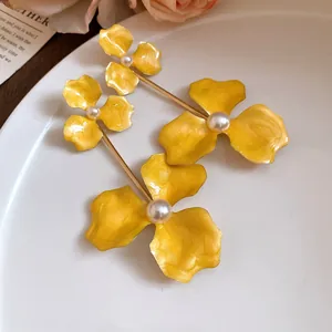 Makro-Detailansicht von leuchtend gelben Emaille-Blumenohrringen mit Perlenakzenten