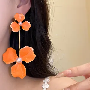 Detailaufnahme eleganter orangefarbener Emaille-Blumenohrringe mit Perlen und Goldstab-Design.