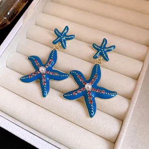 Eleganti orecchini pendenti a stella marina blu con strass rosa e perla centrale