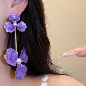 Elegante lila Blumen-Ohrhänger mit Perlen, im Detail am Ohr getragen gezeigt.