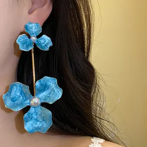 Nahaufnahme von übergroßen blauen Blumenohrringen mit eleganten weißen Perlen