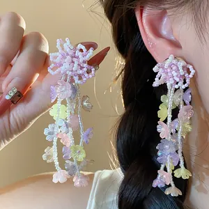 Detailed view of colorful glass beaded flower earrings shown being worn and held