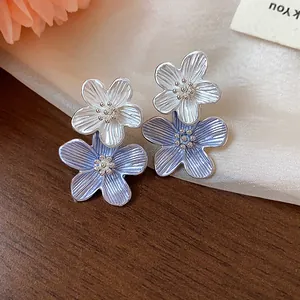 Detailansicht eleganter blau-weißer Emaille-Blumenohrstecker mit Silbernadeln.