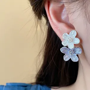 Nahaufnahme von eleganten Doppelblumen-Ohrsteckern mit weißen und blauen Blüten