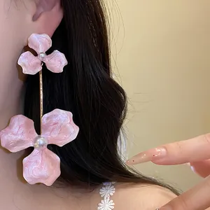 Detailansicht der eleganten rosa Emaille Blumenohrringe mit Perle am Ohr des Models