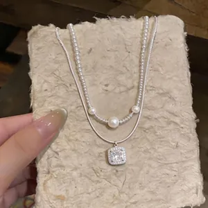 Elegante collana di perle a doppio strato con un ciondolo quadrato in zirconia lucente
