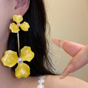 Detailansicht der leuchtend gelben Blumen-Ohrhänger mit weißen Perlen an einer Stahlnadel.