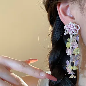 Detail shot of colorful glass beaded flower tassel earrings worn by a model