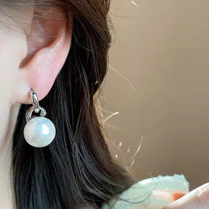 Primo piano di eleganti orecchini a perla rotonda con perno in argento su orecchio.