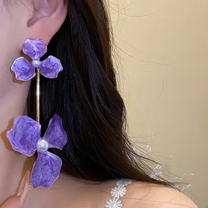 Detailansicht eleganter lila Blumenohrringe mit Perlenakzenten an einem Model für Damen