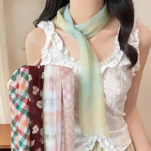 Vista dettagliata di sciarpe lunghe in chiffon leggero con vari motivi floreali e scozzesi.
