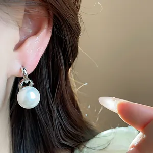 Primo piano di un elegante orecchino con perla bianca e chiusura in argento sul modello
