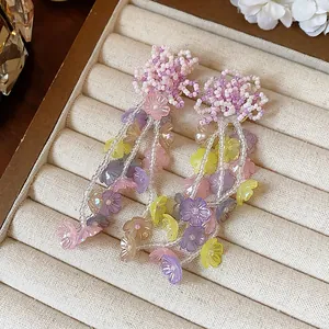 Close-up detail of colorful glass beaded flower tassel earrings on a cream jewelry tray