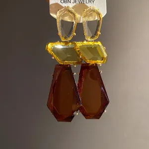 Dettaglio di orecchini pendenti rétro in resina ambra e oro con forme geometriche irregolari