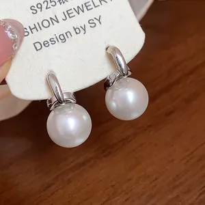 Dettaglio ravvicinato di orecchini con perle tonde e ago in argento S925 su scheda.