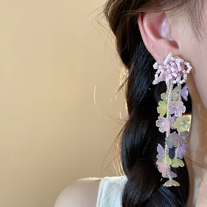 Close-up detail of colorful glass beaded flower tassel earrings worn on a model ear