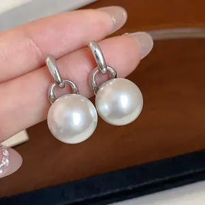 Dettaglio ravvicinato di eleganti orecchini a perno in argento con grandi perle bianche