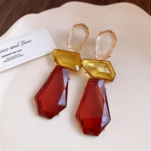 Primo piano di orecchini vintage pendenti in resina irregolare con gemme rosse.
