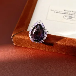 Macro detail of an elegant pear-cut purple zircon ring with halo on brown velvet