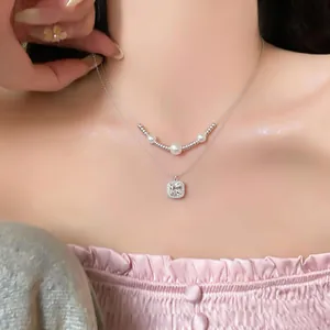 Primo piano di collana d'argento a due strati con ciondolo in zircone quadrato e perle