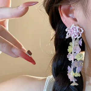 Detail macro view of colorful glass beaded flower tassel earrings worn on an ear