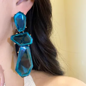 Dettaglio dei grandi orecchini a pendolo in resina blu irregolare dal design vintage