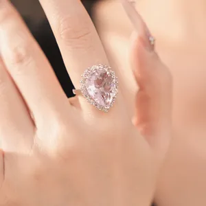 Macro detail showing elegant pear-shaped pink crystal ring with pavé stones on hand