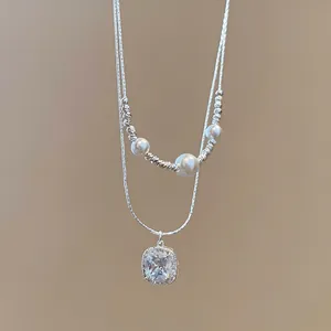 Dettaglio macro del pendente quadrato in zircone e perle sulla collana a doppio filo