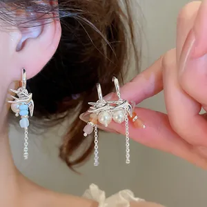 Détail montrant des boucles d'oreilles hirondelles avec perles et chaînes en argent.