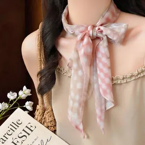 Dettaglio ravvicinato di un foulard in chiffon a quadretti rosa annodato a fiocco