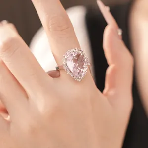 Macro detail of a luxurious pear-shaped pink gemstone ring featuring a crystal halo setting