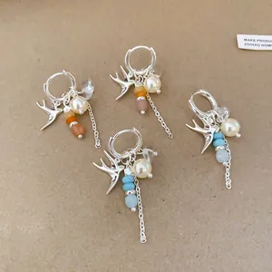 Vue détaillée de boucles d'oreilles créoles hirondelles en argent avec perles et breloques colorées