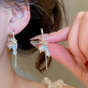 Gros plan de boucles d'oreilles hirondelle en argent avec perles et perles bleues