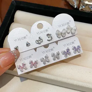 Nahaufnahme eines Sets aus Zirkon-Schmetterlings- und herzförmigen Ohrsteckern auf Karten