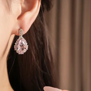 Close-up of elegant pink teardrop zircon earring worn on ear, palace style jewelry