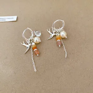 Vue détaillée d'élégantes boucles d'oreilles hirondelle en argent avec perles