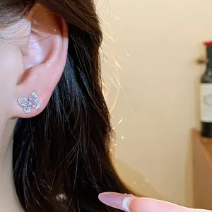 Detailansicht eines eleganten lila Zirkon Schmetterling Ohrsteckers am Ohr eines Models