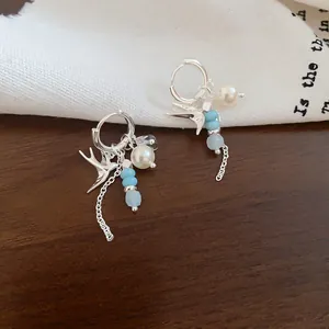 Vue détaillée de boucles d'oreilles créoles hirondelle en argent avec perles bleues