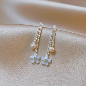 Elegant long tassel earrings with pearls and blue flower petals on silk background